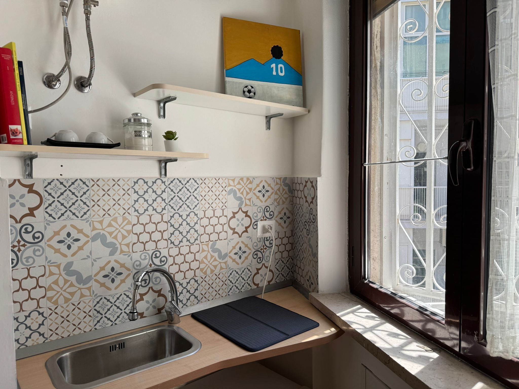 A kitchen with a sink, a window with a view, and decorative tiles.