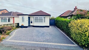 A residential house with a paved driveway, a front door, and a small garden area.
