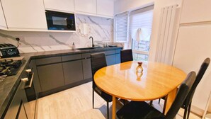 A modern kitchen with a built-in microwave, a sink, and a dining area with a wooden table and black chairs.