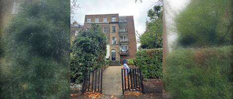 A residential building with a brick facade, a front entrance, and a gated driveway.