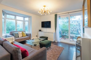 A modern living room with a sofa, a coffee table, and a TV mounted on the wall.