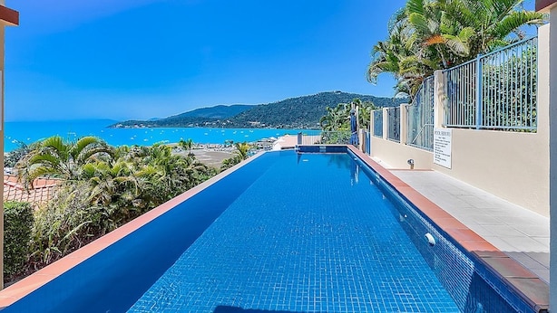 Una piscina con vistas al mar y una colina al fondo.