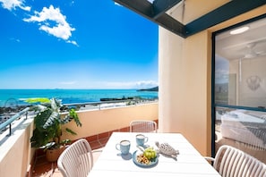 A balcony with a table set for two, overlooking a coastal view with the sea and boats. - Blue Beyond Airlie (Airlie Beach)