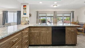 A modern kitchen with a central island, wooden cabinets, and a dishwasher. - 55+ Comfort & Quiet | 2BR Peaceful Home (Sun City West)