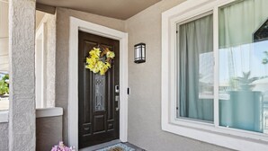A front door with a dark wood finish, a doormat with "HOME" written on it, and a small potted plant with flowers. - 55+ Comfort & Quiet | 2BR Peaceful Home (Sun City West)