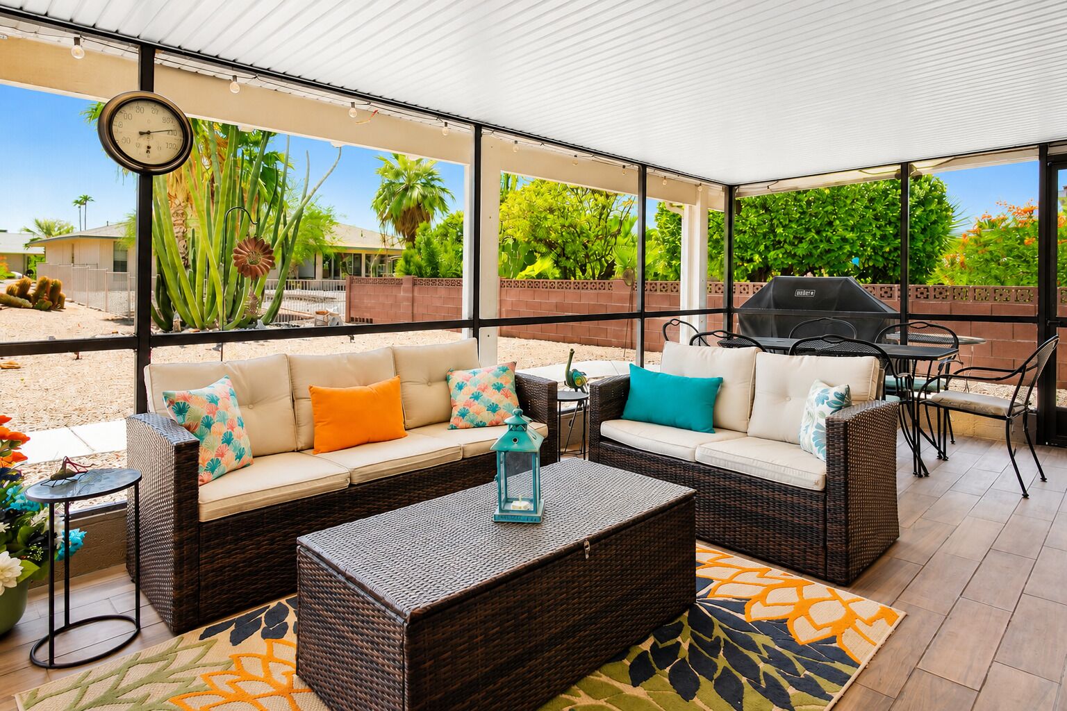 A covered patio area with wicker furniture, a grill, and a clock.
