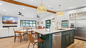 Una cocina moderna con una isla grande, electrodomésticos de acero inoxidable e iluminación colgante.