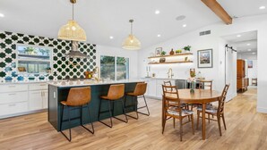 Una cocina moderna con una isla central, taburetes de bar e iluminación colgante.