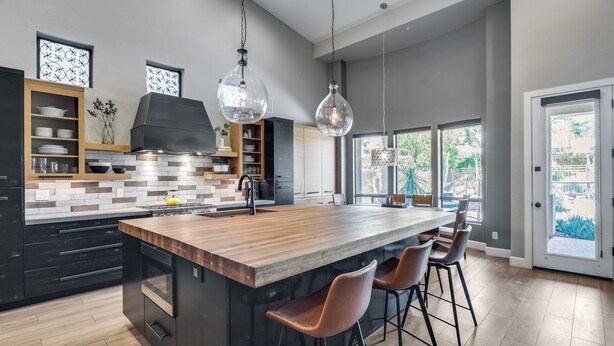 A modern kitchen with a large island, bar stools, and pendant lighting.