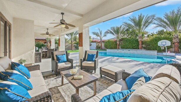An outdoor patio with wicker furniture, a pool, and palm trees. - Desert Haven: Pool, SPA, Mini-Golf, and More (Indio)