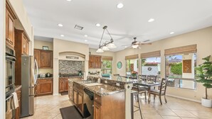 A spacious kitchen with granite countertops, wooden cabinets, and a large island. - Desert Haven: Pool, SPA, Mini-Golf, and More (Indio)