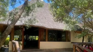 A thatched-roof structure with a wooden deck and a stone pathway leading to it.