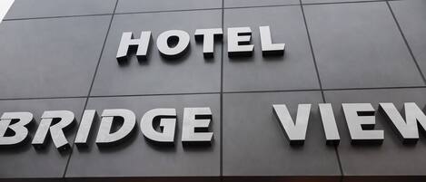 A modern hotel sign with the words "HOTEL BRIDGE VIEW" in large, white letters on a grey facade.