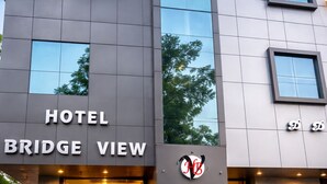 Et hotel kaldet "HOTEL BRIDGE VIEW" med en moderne facade og store vinduer der spejler træer.