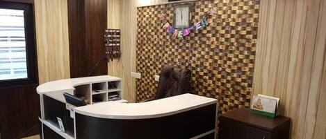 A reception area with a check-in counter, a reception desk, a wall clock, and a bulletin board with a 'RECEPTION' sign.