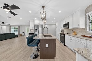 A modern kitchen with white cabinets, a granite countertop, and stainless steel appliances.