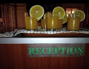 Ein Empfangsbereich mit einem Schild mit der Aufschrift 'RECEPTION' und mehreren Gläsern Orangensaft mit Zitronenscheiben auf einem Tisch.
