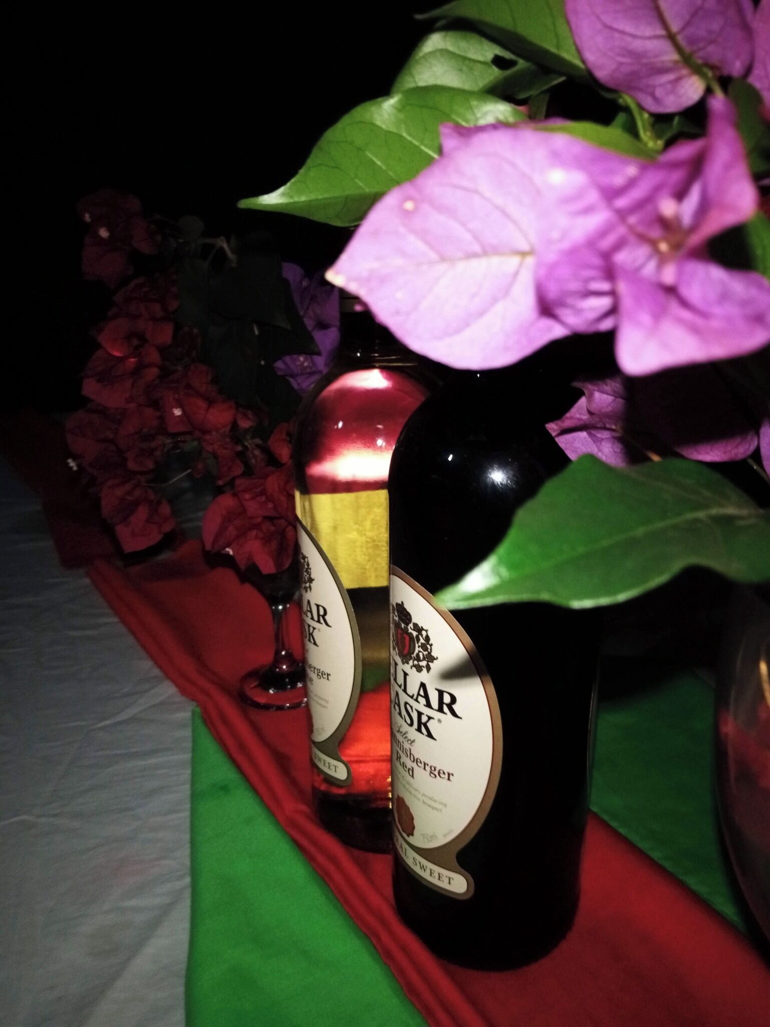 Two bottles of wine on a table with a red cloth.