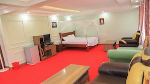 Una habitación de hotel con cama, televisión, escritorio, silla y sofá.