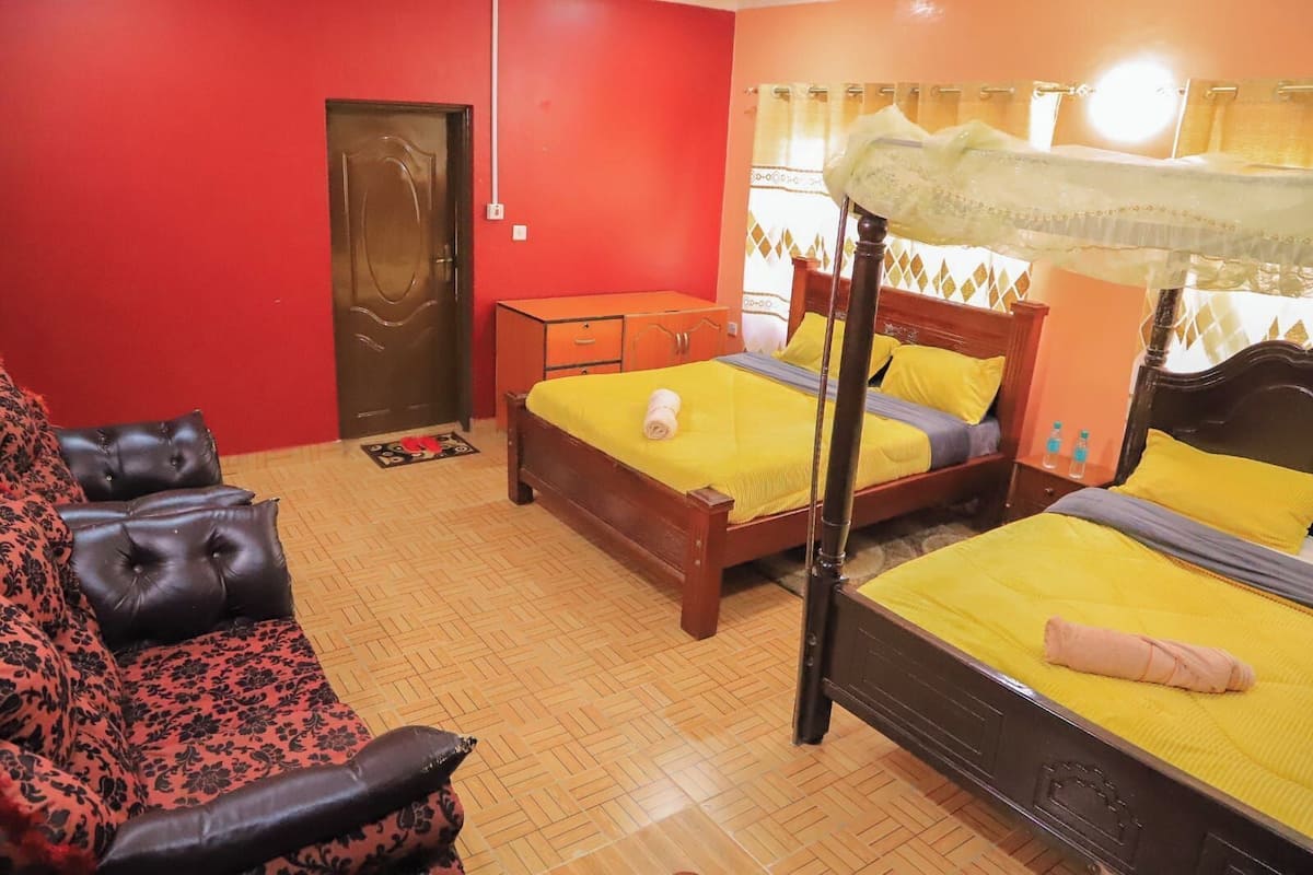 Una habitación con dos camas de madera, un sofá y un armario.
