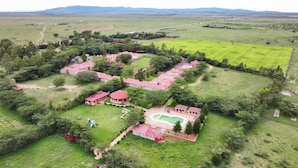 Vista aérea de una propiedad rural con varias construcciones, una piscina y campos verdes circundantes.