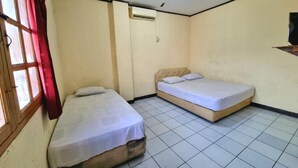 Un alojamiento pequeño y de una sola habitación, con dos camas, una ventana con cortinas rojas y una lámpara en el techo.