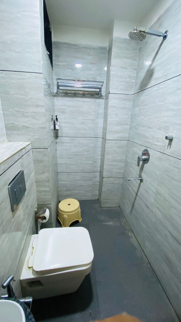 A small, compact bathroom with a toilet, a sink, and a shower.