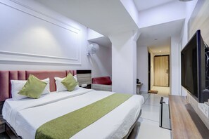 Una habitación de hotel con una cama grande, un televisor y una silla roja.