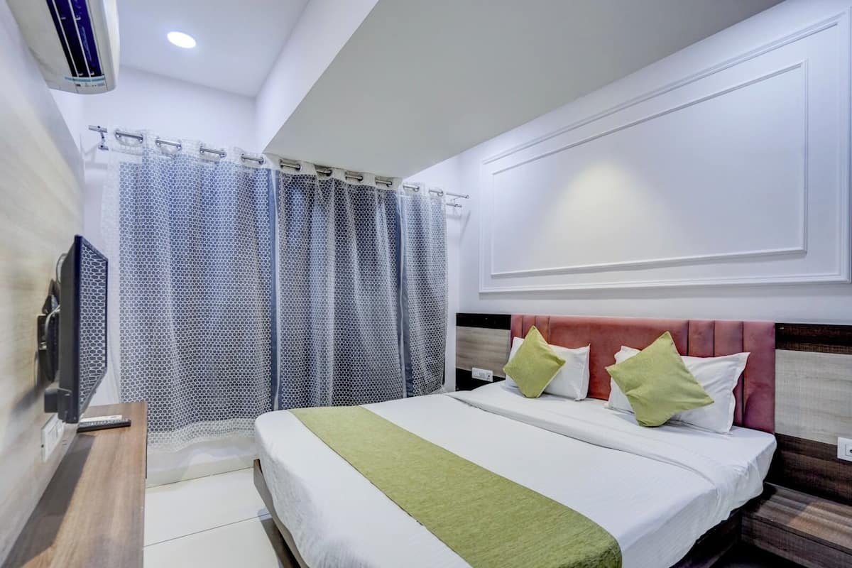 Een hotelkamer met een bed, een televisie, een douchegordijn en een wandairconditioner.