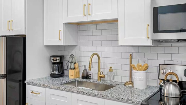 A kitchen with white cabinets, a granite countertop, a stainless steel sink, a coffee maker, and a kettle. - Private 1 bedroom luxury mother-in-law suite close proximity to Midtown Tampa (Tampa)