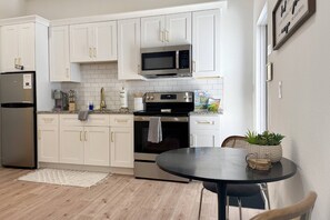 A modern kitchen with white cabinets, stainless steel appliances, and a round dining table.