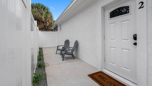 A white house with a door marked '2', a small patio with two chairs, and a welcome mat. - Private King studio for 2 in close proximity to Midtown Tampa (Tampa)