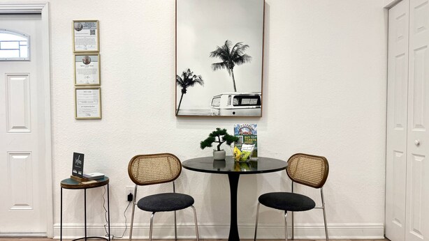 A dining area with a round table, two chairs, a small side table with a plant, and framed certificates on the wall. - Private King studio for 2 in close proximity to Midtown Tampa (Tampa)