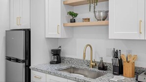 A kitchen with white cabinets, a black refrigerator, granite countertops, a stainless steel sink, and a coffee maker. - Private King studio for 2 in close proximity to Midtown Tampa (Tampa)