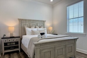 A bedroom with a bed, two bedside tables, a window with blinds, and a nightstand with a lamp. - Midtown Stay with 2 bedrooms less than a mile from the RJ Stadium (Tampa)