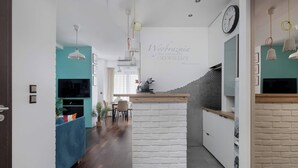 Una cocina moderna con pared decorativa de ladrillo blanco, encimeras de madera e iluminación colgante.