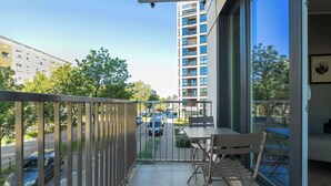 A balcony with a view of a parking lot and a tall building.