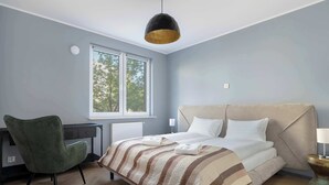 A bedroom with a bed, a desk, a chair, and a window.