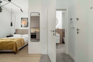 Un dormitorio moderno con cama, mesita de noche y espejo.