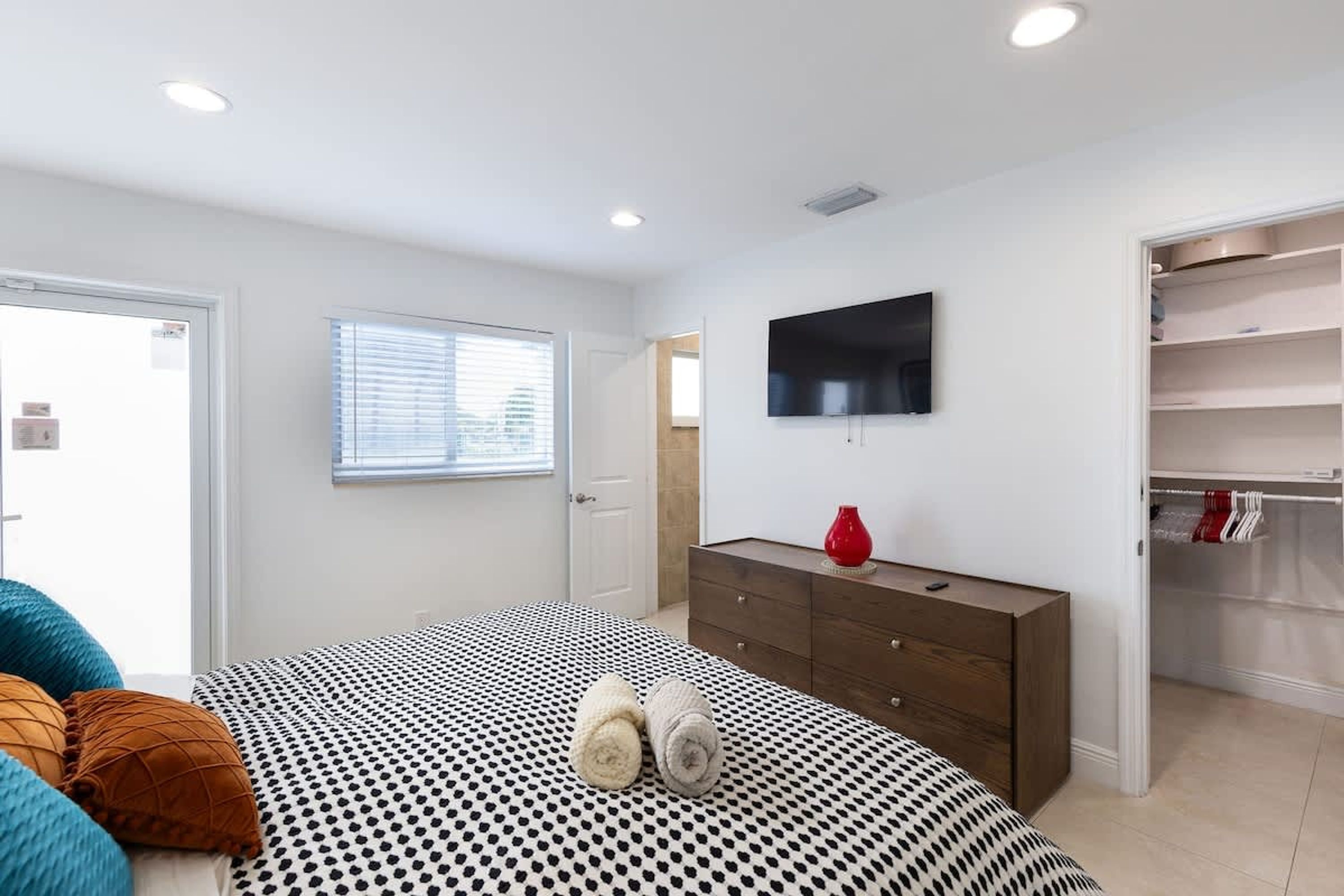 A bedroom with a bed, a dresser, a TV, and a closet.