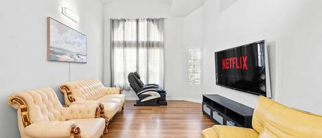 A living room with a sofa set, a massage chair, a TV, and a painting on the wall.