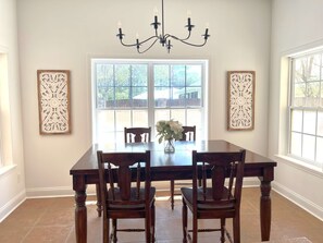 A dining room with a large wooden table, four chairs, a chandelier, and two decorative panels on the walls. - Aqua Dream - Home for 11 (St. Augustine)
