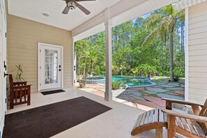 A covered porch with a view of a swimming pool and tropical vegetation. - Aqua Dream - Home for 11 (St. Augustine)