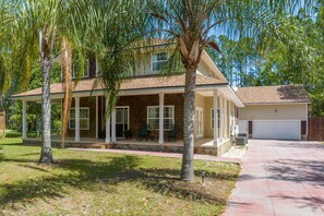 A two-story house with a covered porch, a garage, and a well-maintained lawn. - Aqua Dream - Home for 11 (St. Augustine)