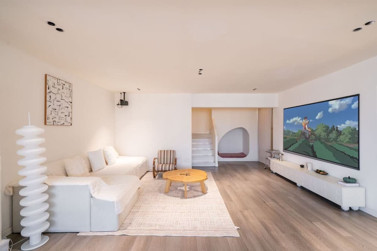 Una sala de estar moderna con un sofá, una mesa de centro, un televisor y una zona de estar circular y original.