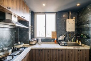A kitchen with a stove, oven, and a window with a city view. - Book and Bed-Lujiabang (Shanghai)