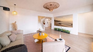 Una sala de estar moderna con un sofá, una mesa amarilla y un cuadro grande de una playa.