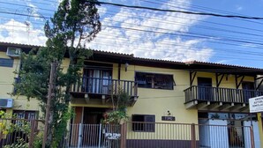 A yellow building with balconies, a gated entrance, and a sign indicating a simulation center. - Pousada Jardim das Estações (Itatiaia)
