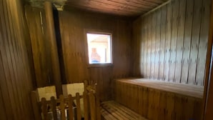 A wooden room with a bench, a small window, and a blue trash bin. - Pousada Jardim das Estações (Itatiaia)