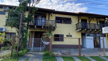 Um edifício amarelo com varandas, entrada fechada por portão e uma placa indicando um centro de simulação.
